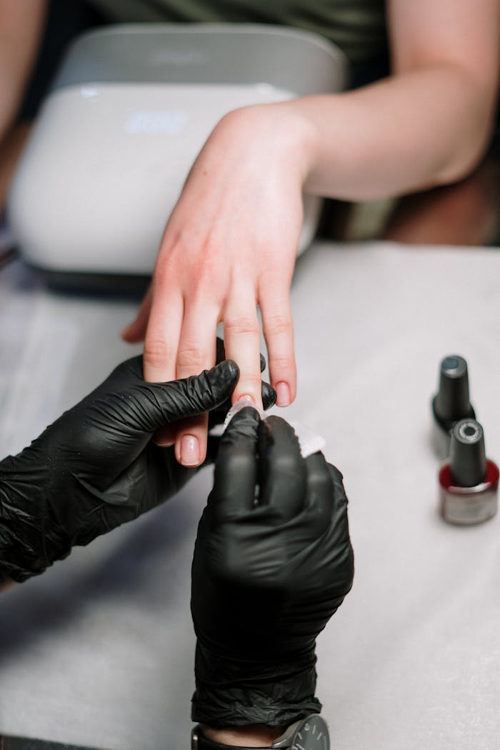 services-03 Close-up of a professional manicure with gel polish and black gloves in a salon.